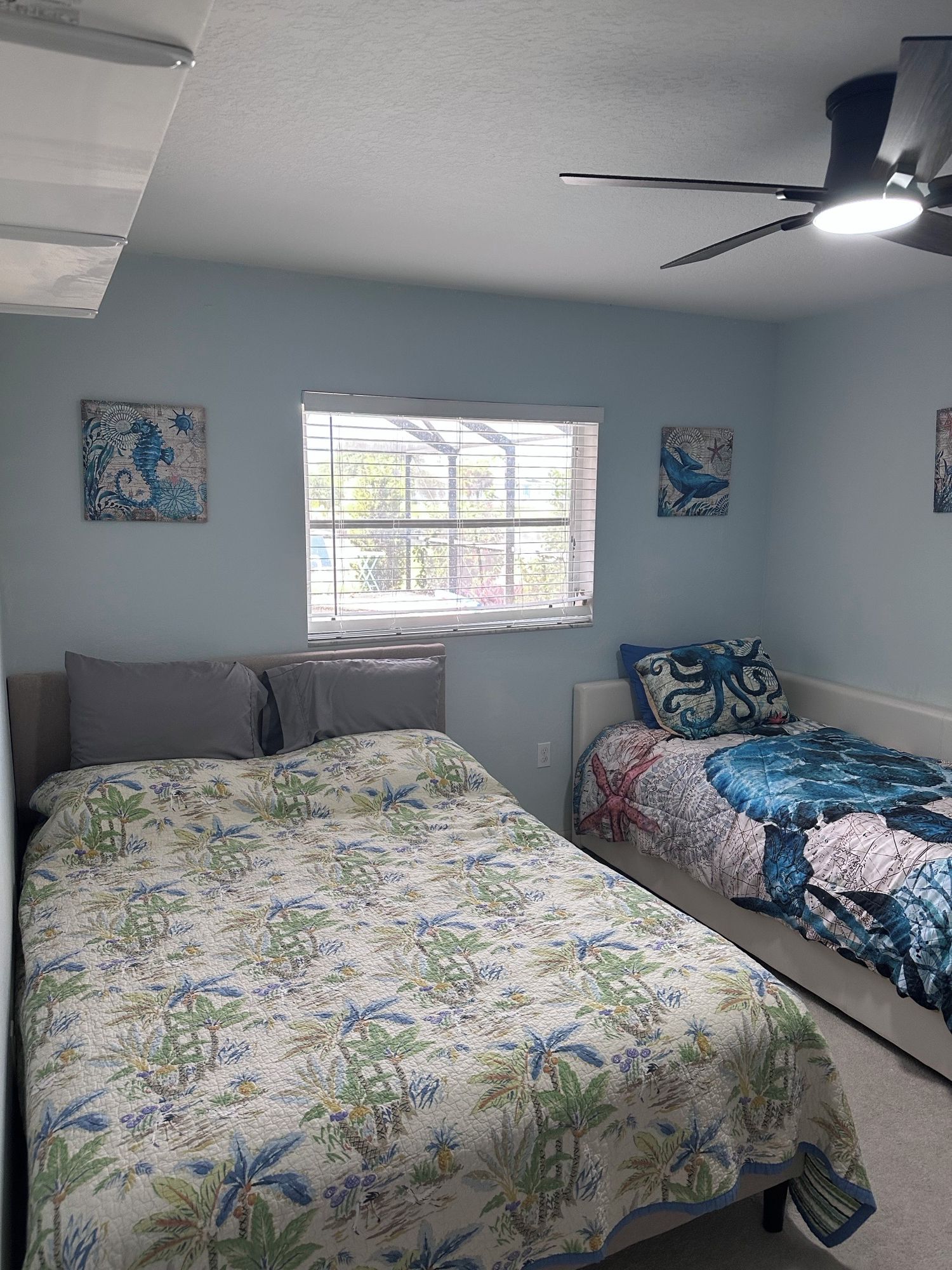 A bedroom with two beds, a window with blinds, and ceiling fans.