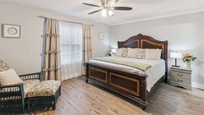 Un dormitorio con una cama de madera, una silla, una mesita de noche y un ventilador de techo.