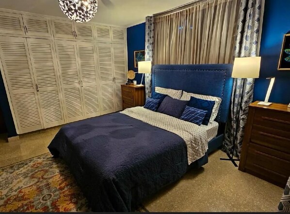 Un dormitorio con cama, mesita de noche, cómoda, armario y candelabro.