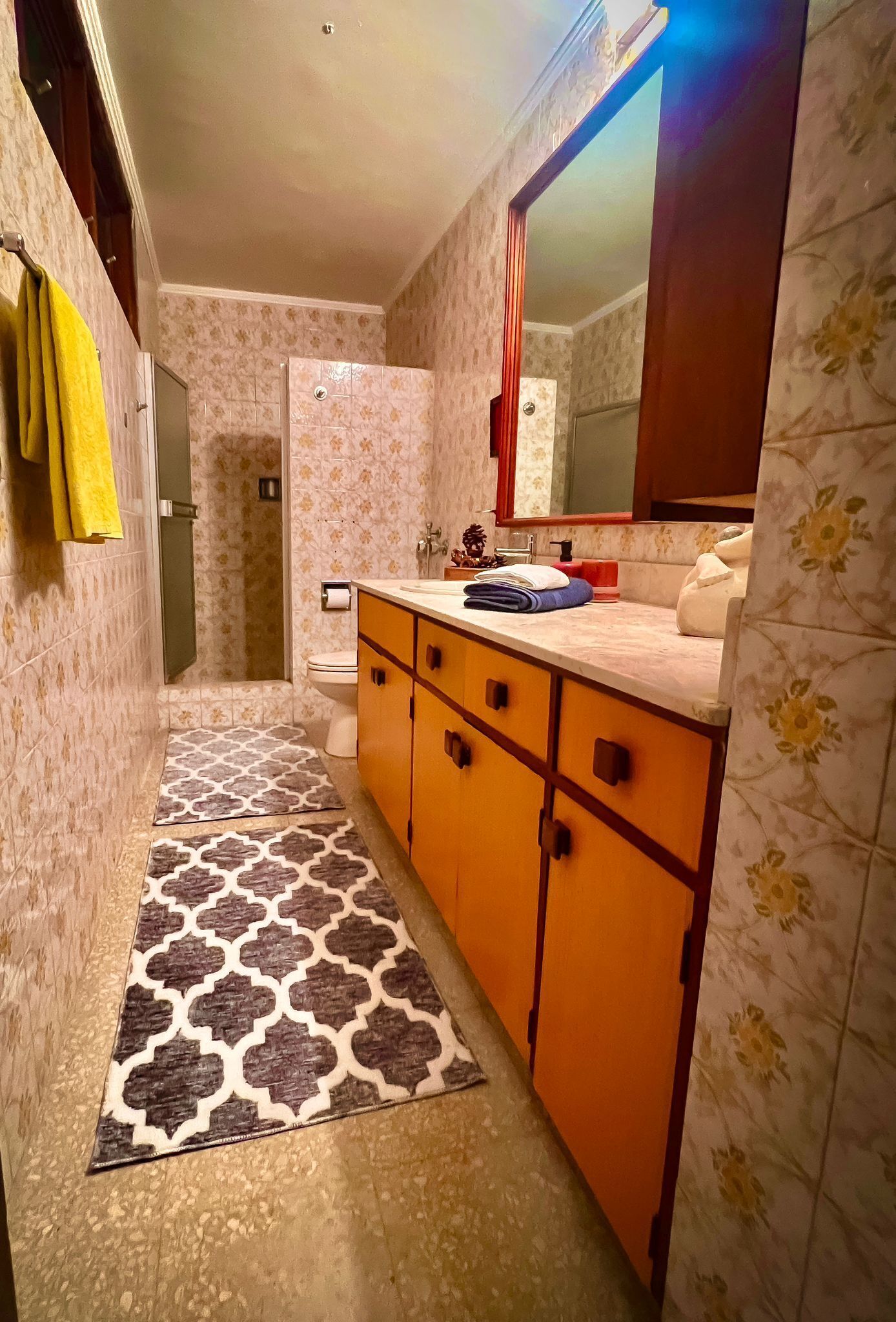 Un baño con ducha, inodoro y lavamanos con espejo.