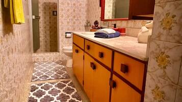 Un baño con ducha, inodoro y lavamanos con espejo.