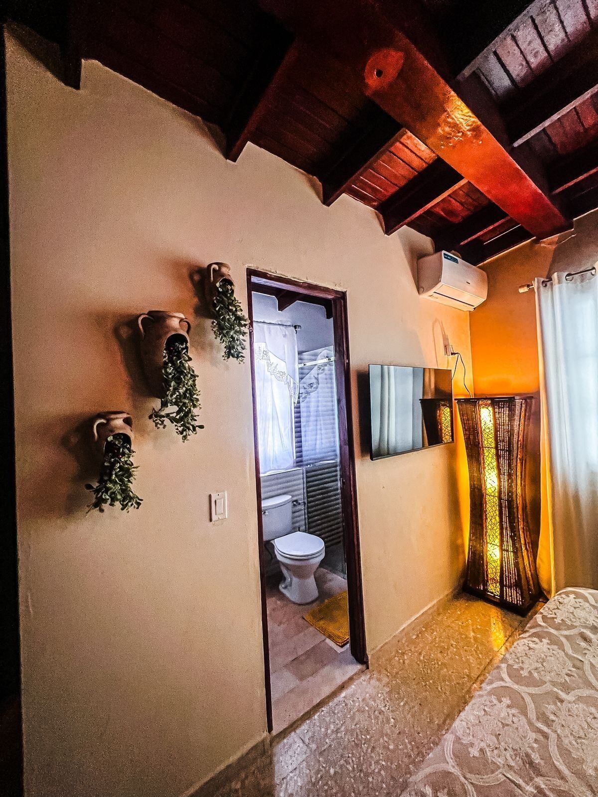 A bathroom with a toilet, shower, and a mirror. There are two wall-mounted planters with greenery.
