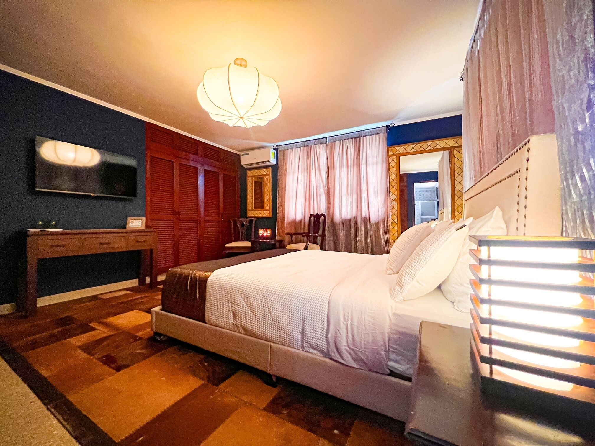 Een hotelkamer met een groot bed, een bureau, een televisie en een spiegel.