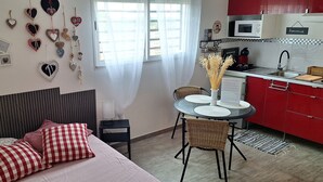A bedroom with a bed, checkered pillows, a bedside table, and a wall decorated with heart-shaped items.