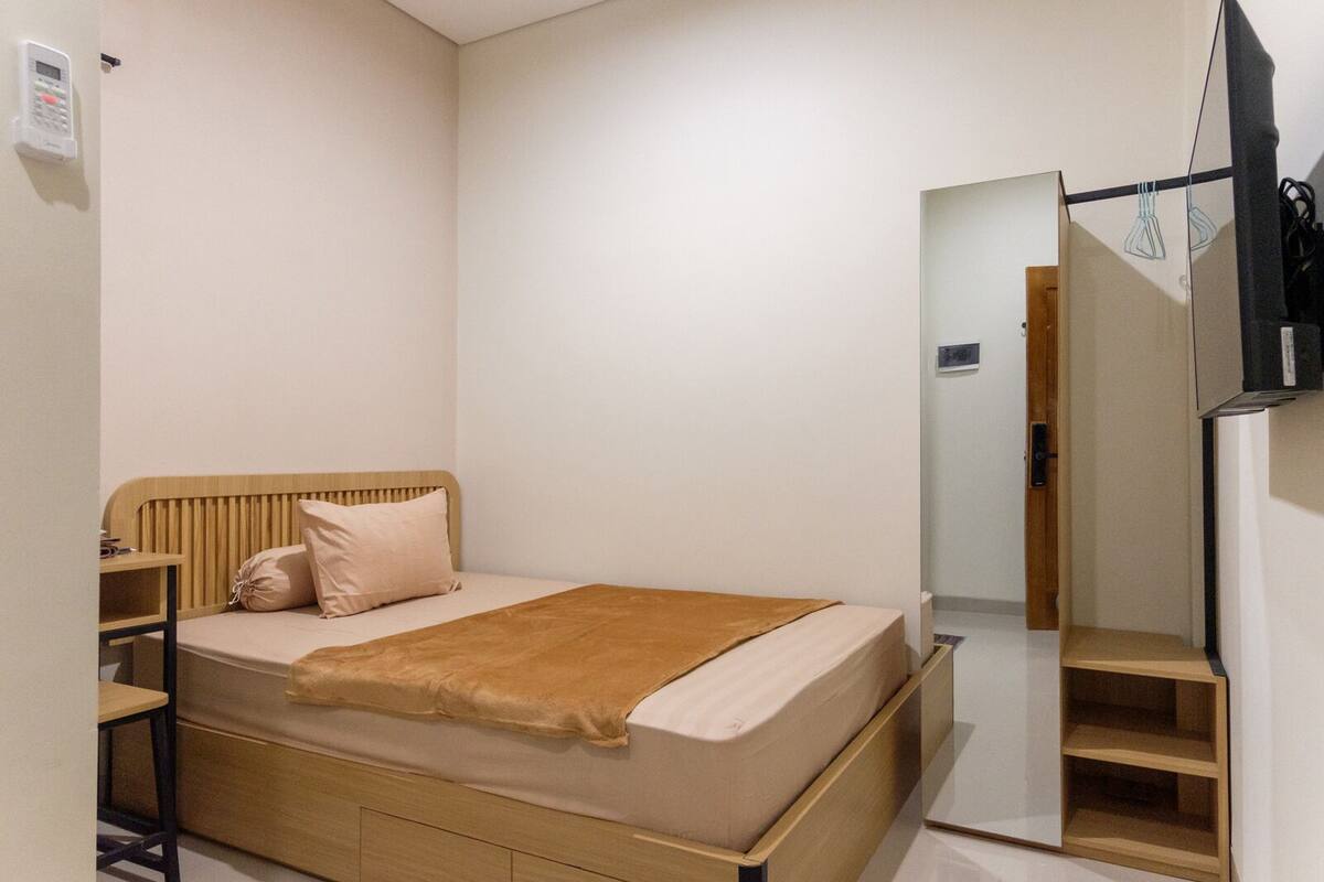 A bedroom with a wooden bed, a bedside table, a mirror, and a wardrobe.
