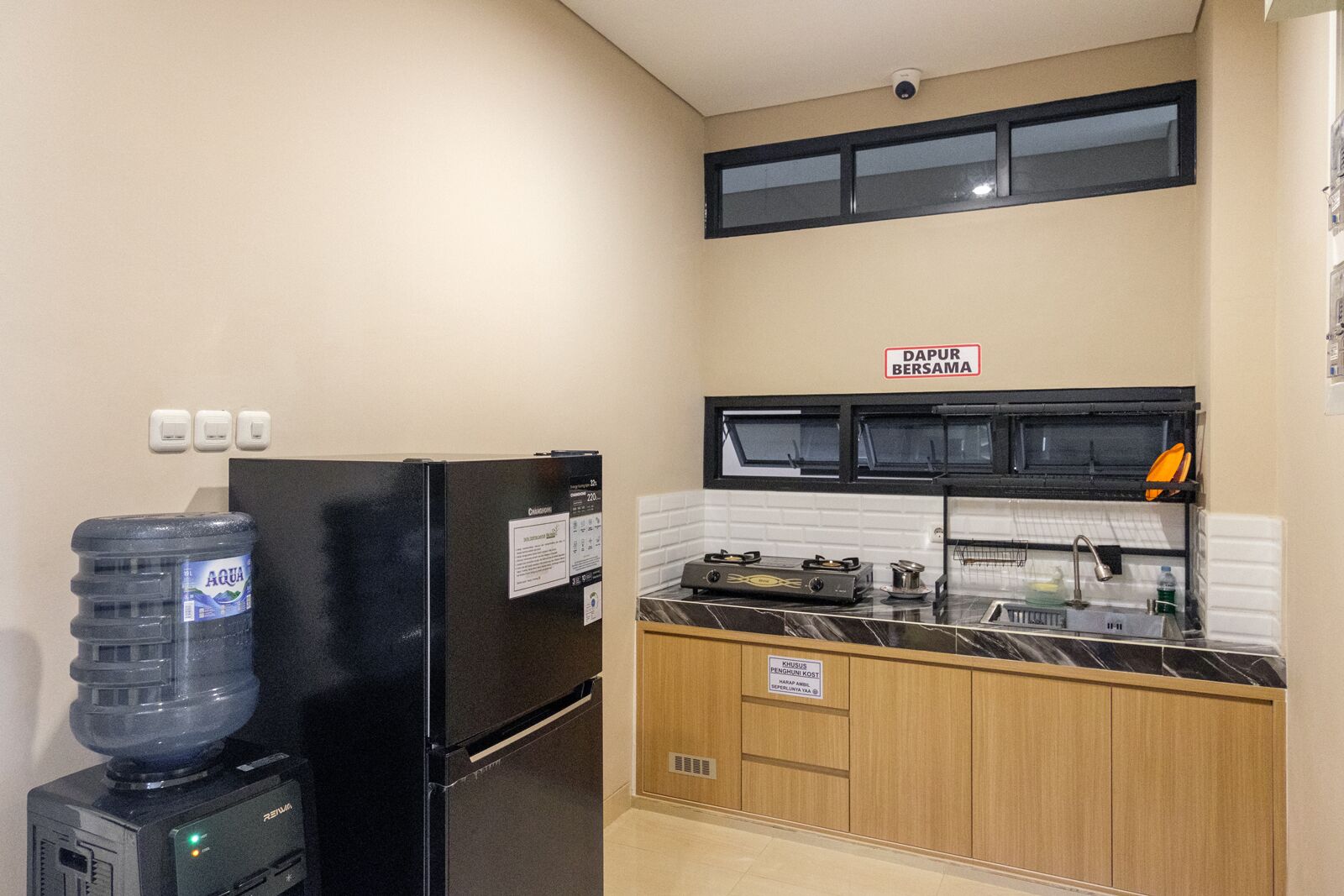 Una cocina compacta con refrigerador, dispensador de agua, estufa y pileta.