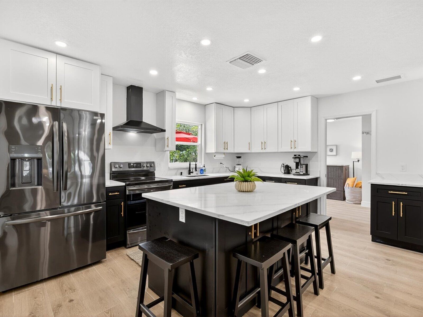 A modern kitchen with stainless steel appliances, white cabinetry, and a central island with bar stools.