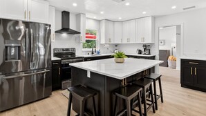 A modern kitchen with stainless steel appliances, white cabinetry, and a central island with bar stools.