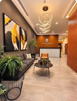 A modern hotel lobby with a reception desk, seating area, and artwork.