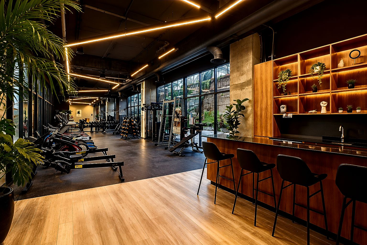 A gym with exercise equipment, a wooden reception desk, and large windows.