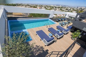 A rooftop pool with lounge chairs and a view of the city.