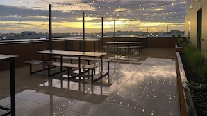 An outdoor patio with string lights, wooden tables, and benches. - Cityscape minutes walk from all the city offers (Christchurch)