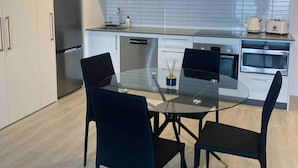 A modern kitchen with white cabinets, a glass dining table, and black chairs. - Cityscape minutes walk from all the city offers (Christchurch)