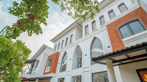 Un immeuble à plusieurs étages, doté d’une façade blanche, de détails en briques rouges et de nombreuses fenêtres.