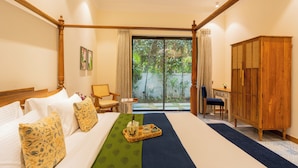 Une chambre d’hôtel avec un grand lit, un bureau, une armoire et une vue sur la verdure environnante.