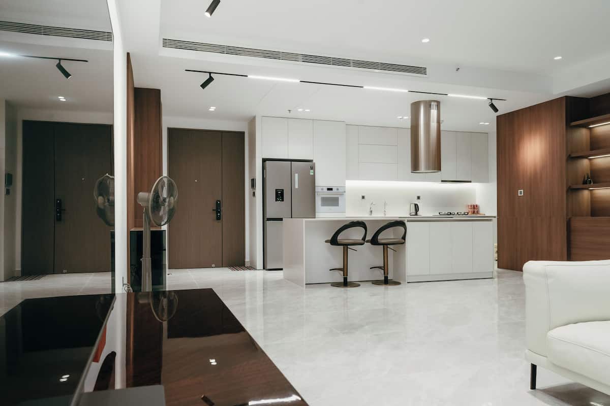 A modern kitchen with white cabinets, stainless steel appliances, and a central island with bar stools.