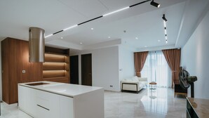 A modern kitchen with a central island, recessed lighting, and a large window with curtains. - Midtown Premium Apartments (Ho Chi Minh City)