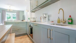 Moderni keittiö, jossa on vaaleansiniset kaapit, sisäänrakennettu uuni, kahvinkeitin ja pesuallas, jossa on kullanvärinen hana.