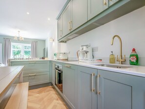 Une cuisine moderne avec des meubles bleu clair, un four encastré, une machine à café et un évier avec un robinet doré.
