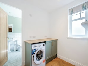 A laundry room with a washing machine, grey cabinets, and a window.