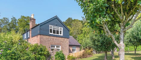 A house with a stone facade, a pitched roof, and a well-maintained lawn.