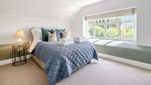 A bedroom with a bed, pillows, a bedside table with a lamp, a window with a view, and a ceiling light fixture. - 3 bedroom accommodation in Kirkton of Lethendy (Kirkton of Lethendy)