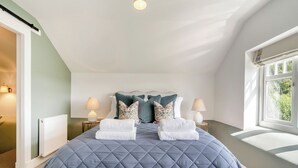 A bedroom with a large bed, two bedside lamps, a radiator, and a window with a view of greenery. - 3 bedroom accommodation in Kirkton of Lethendy (Kirkton of Lethendy)