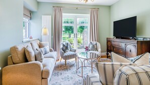 A living room with a sofa, armchairs, a TV, a chandelier, and a view of the outdoors. - 3 bedroom accommodation in Kirkton of Lethendy (Kirkton of Lethendy)