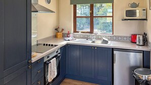 A kitchen with a stove, sink, microwave, and a window with a view of greenery.