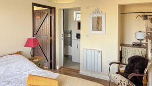 A bedroom with a bed, a chair, a radiator, and a door leading to another room.