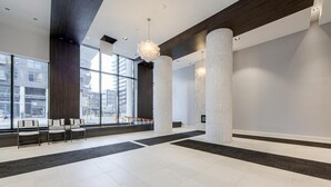 A spacious lobby with large windows, high ceilings, and modern lighting fixtures.