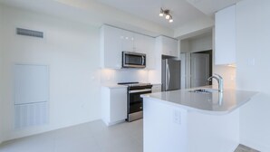 A modern kitchen with white cabinetry, stainless steel appliances, and a central island with a sink.