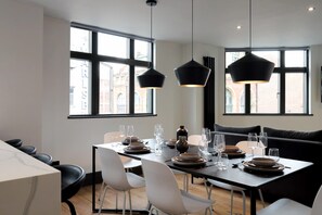 A modern dining area with a table set for four, large windows, and black pendant lights.