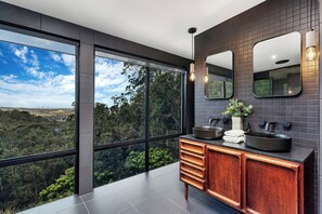 Une salle de bain moderne avec une grande fenêtre, un meuble-lavabo en bois et un lavabo noir.