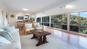 A spacious living area with a large window, a dining table, and a sofa.