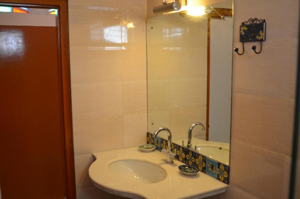 A bathroom with a sink, mirror, and tiled walls.
