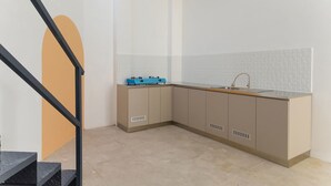 A modern kitchen with a built-in stove, sink, and cabinets. - Ipnoss Coliving Semarang, by INNCA COLLECTION (Semarang)