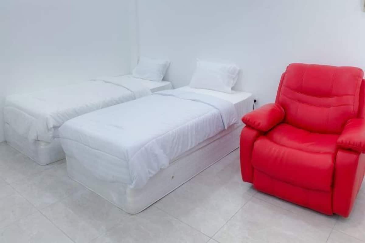 A room with two single beds and a red chair.