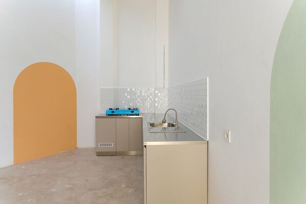 A compact kitchen with a gas stove, sink, and a small cabinet. - Ipnoss Coliving Semarang, by INNCA COLLECTION (Semarang)