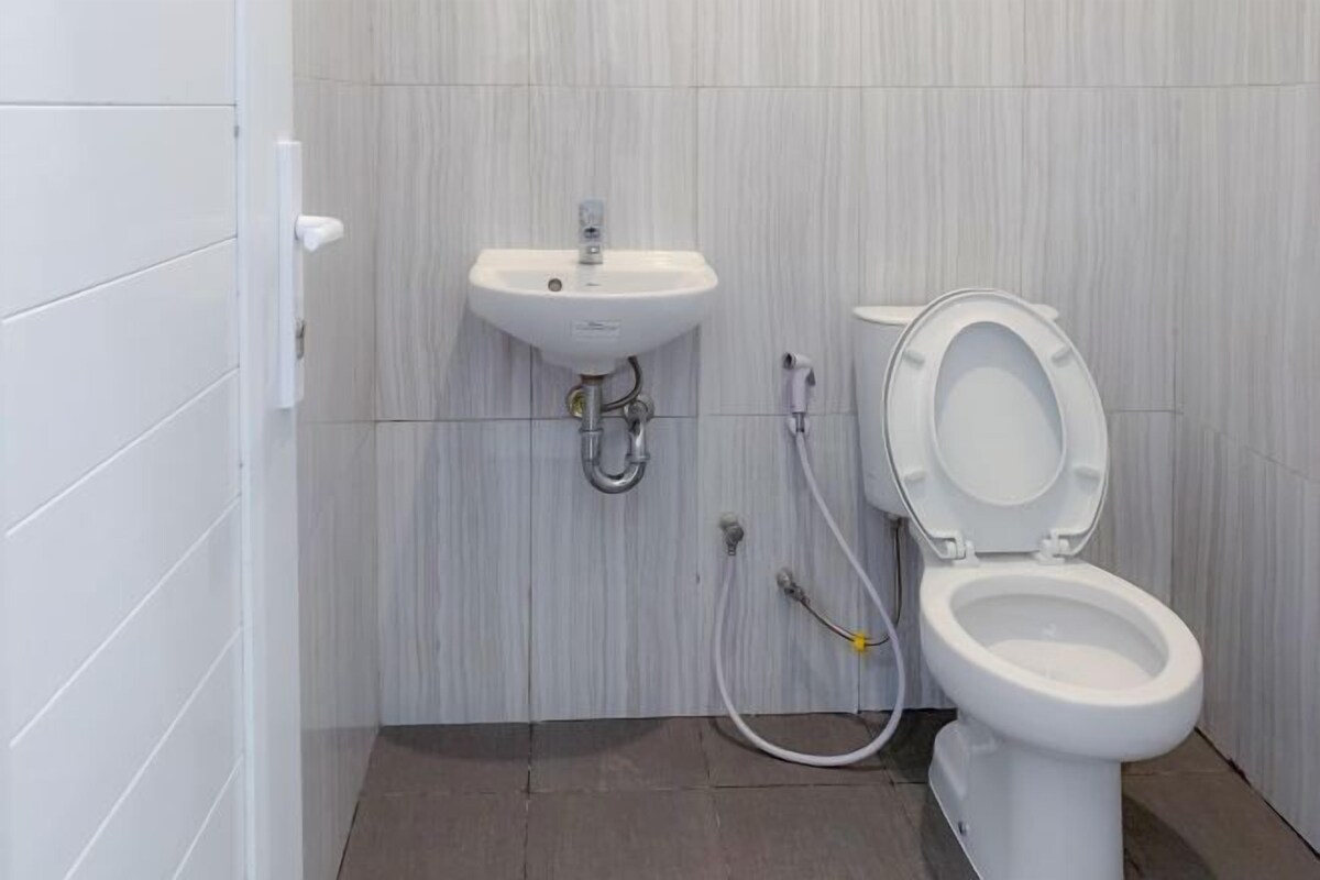 Une salle de bain avec un lavabo blanc, des toilettes et des murs carrelés.