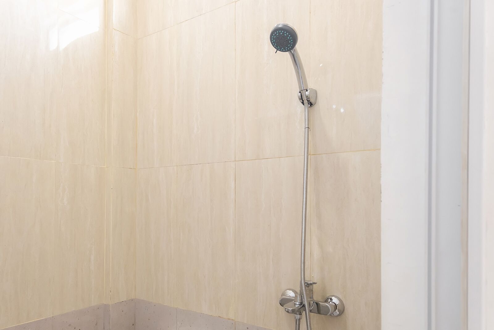 A shower with a handheld showerhead and a wall-mounted faucet.