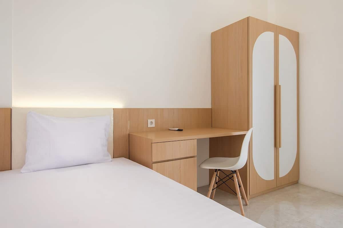 A bedroom with a bed, a desk, and a wardrobe.