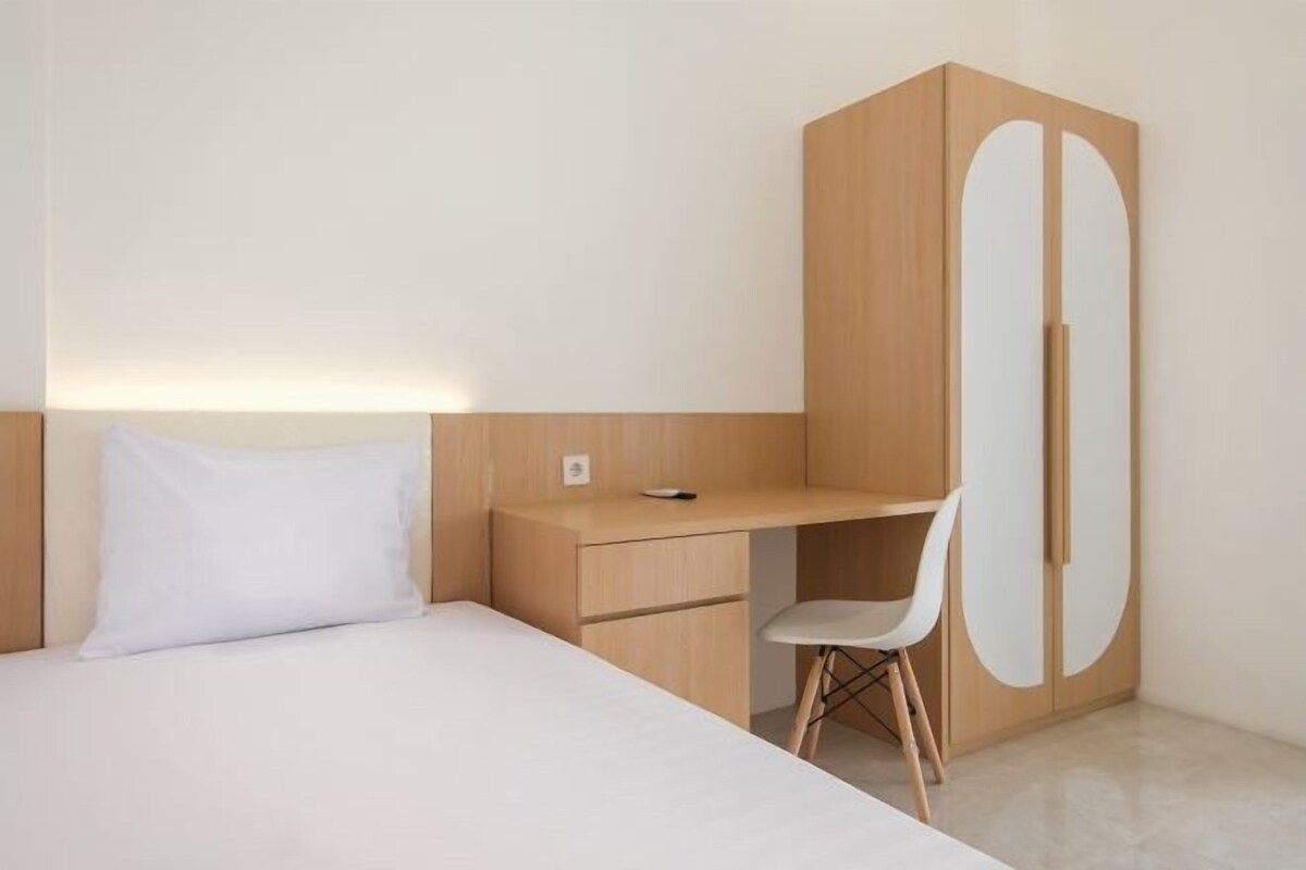 Une chambre à coucher au style minimaliste, avec un lit, un bureau et une armoire.