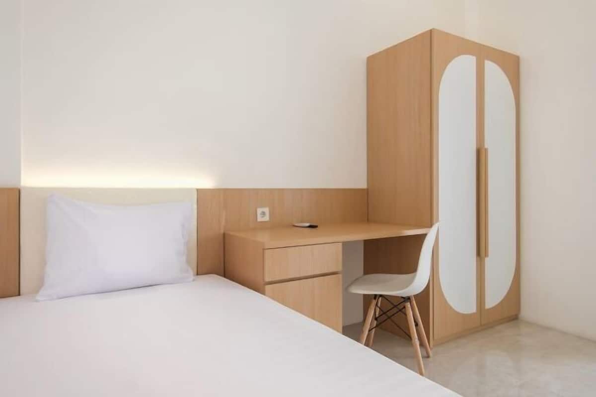 A minimalist bedroom with a bed, a desk, and a wardrobe.