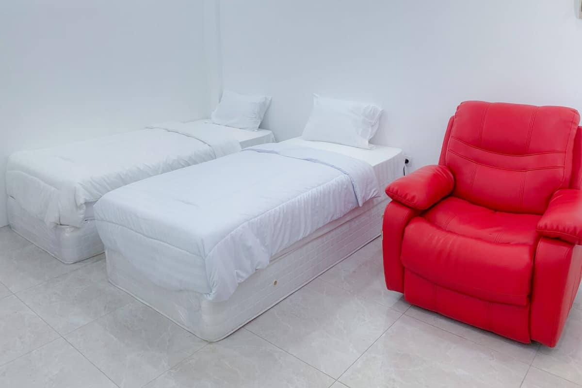 A room with two single beds and a red chair.