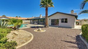 Una casa moderna con piscina, una palmera y un área de patio.