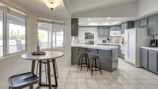 Una cocina moderna con una isla central, taburetes de bar y una mesa de comedor.