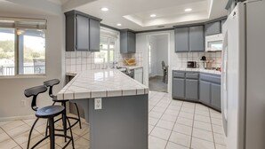 Una cocina moderna con gabinetes grises, encimera blanca y una isla integrada con taburetes de bar.