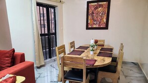 A dining area with a round wooden table, six chairs, and a red sofa. - Hidden Gem in Ouakam [Mamelles] (Dakar)