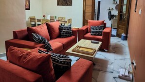 A living room with a red sofa set, a wooden coffee table, and a painting on the wall. - Hidden Gem in Ouakam [Mamelles] (Dakar)